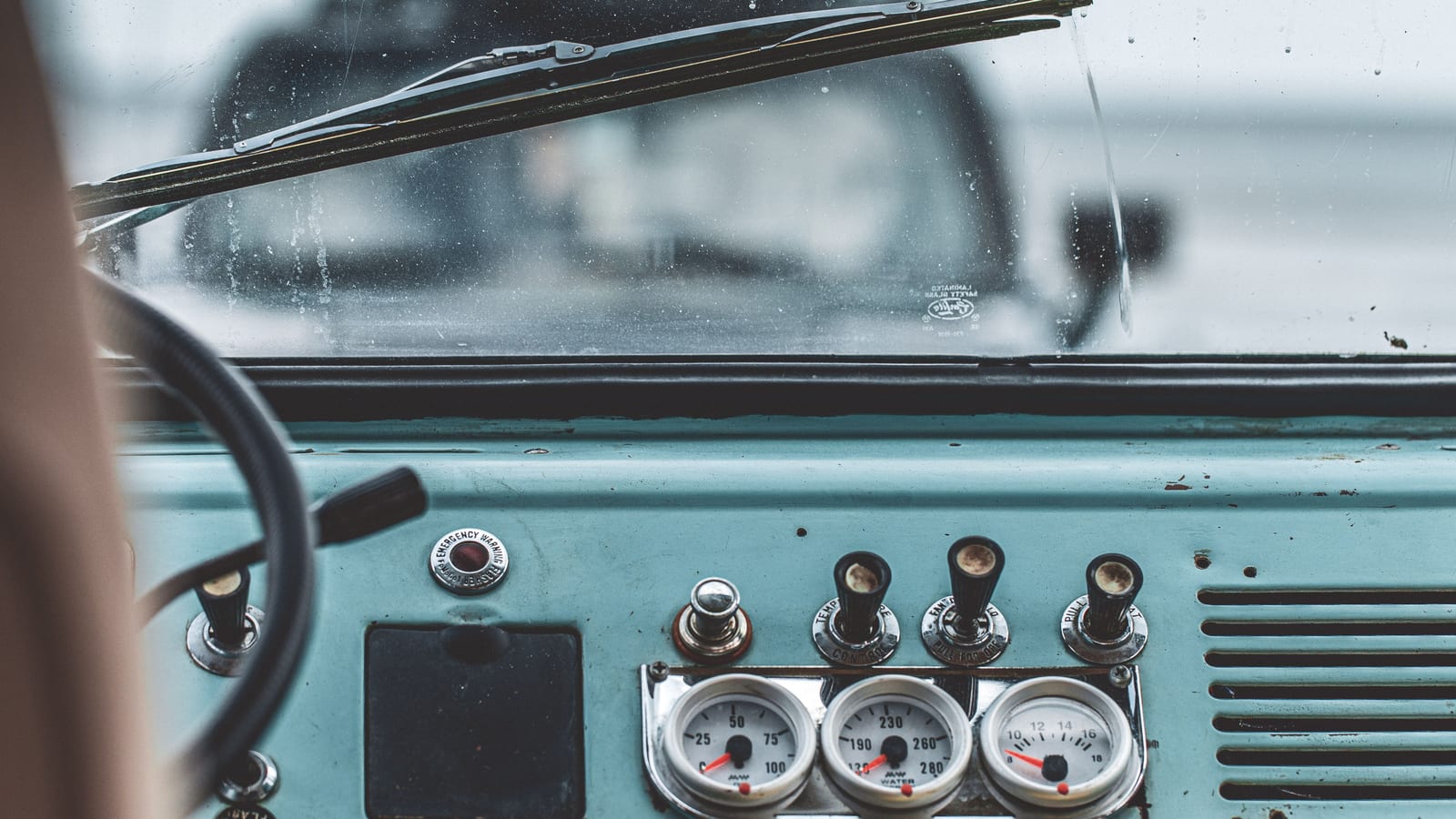 Detailed view of a vintage car interior showing dashboard gauges, steering wheel, and windshield.