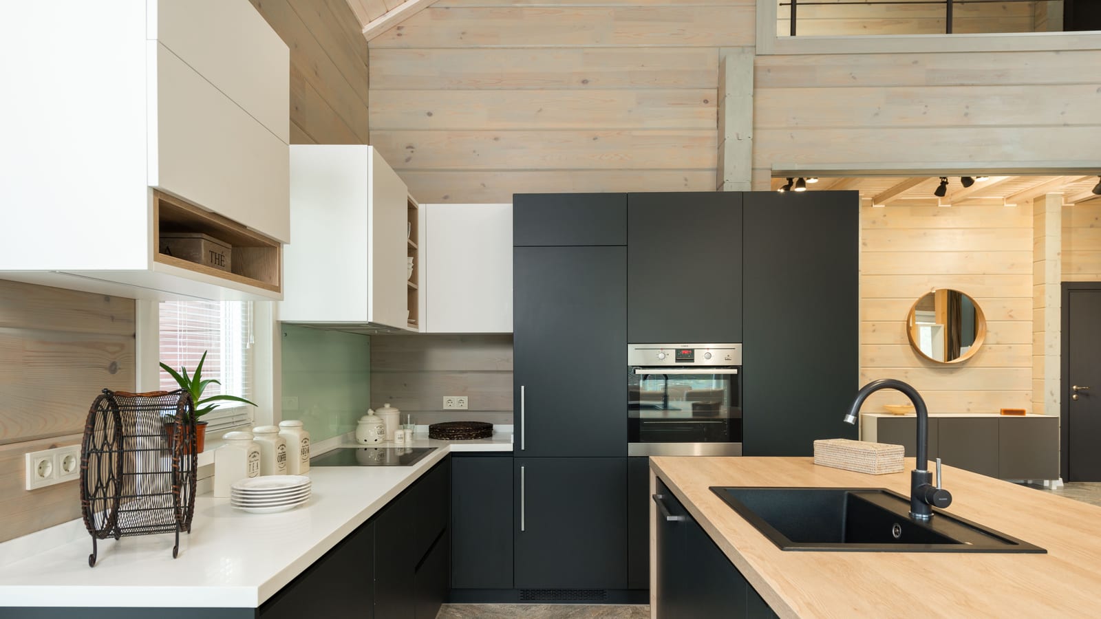 Interior of stylish kitchen with minimalist black and white cabinets built in oven and stove with sink in counter