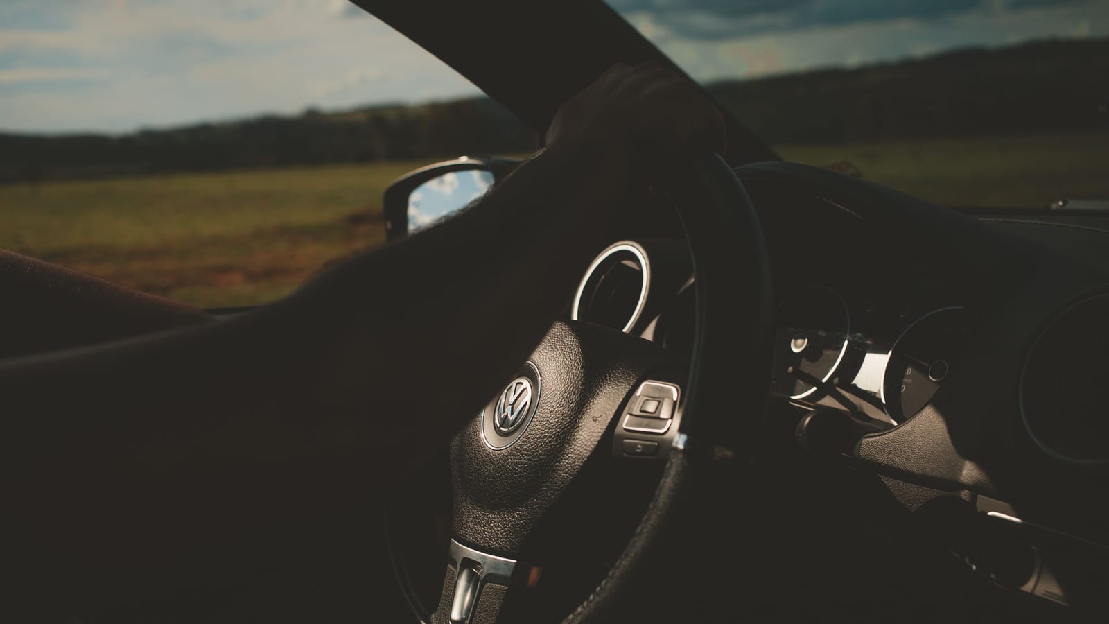 Close-up of a car interior with a focus on the steering wheel and dashboard.