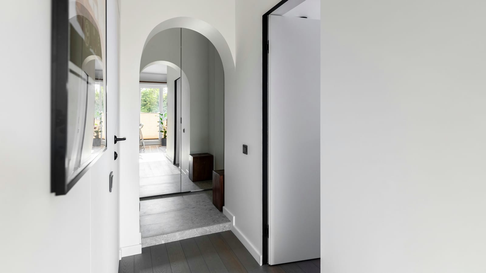 Modern white hallway with arched doorways and dark flooring
