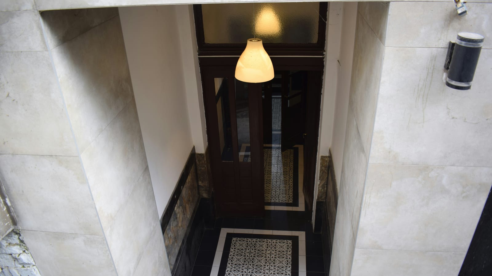 Interior hallway with patterned floor tiles and lamp